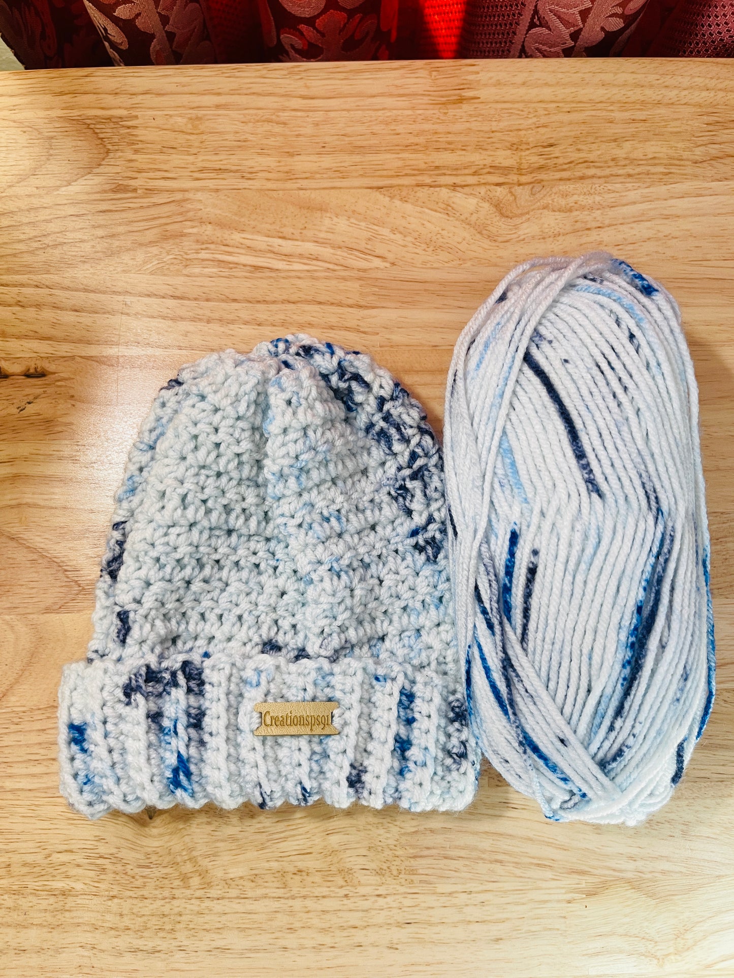 Pink crocheted beanie and yarn on a wooden surface, made with 100% premium acrylic yarn, circumference 14" with stretch 16" washable and tumble dry 