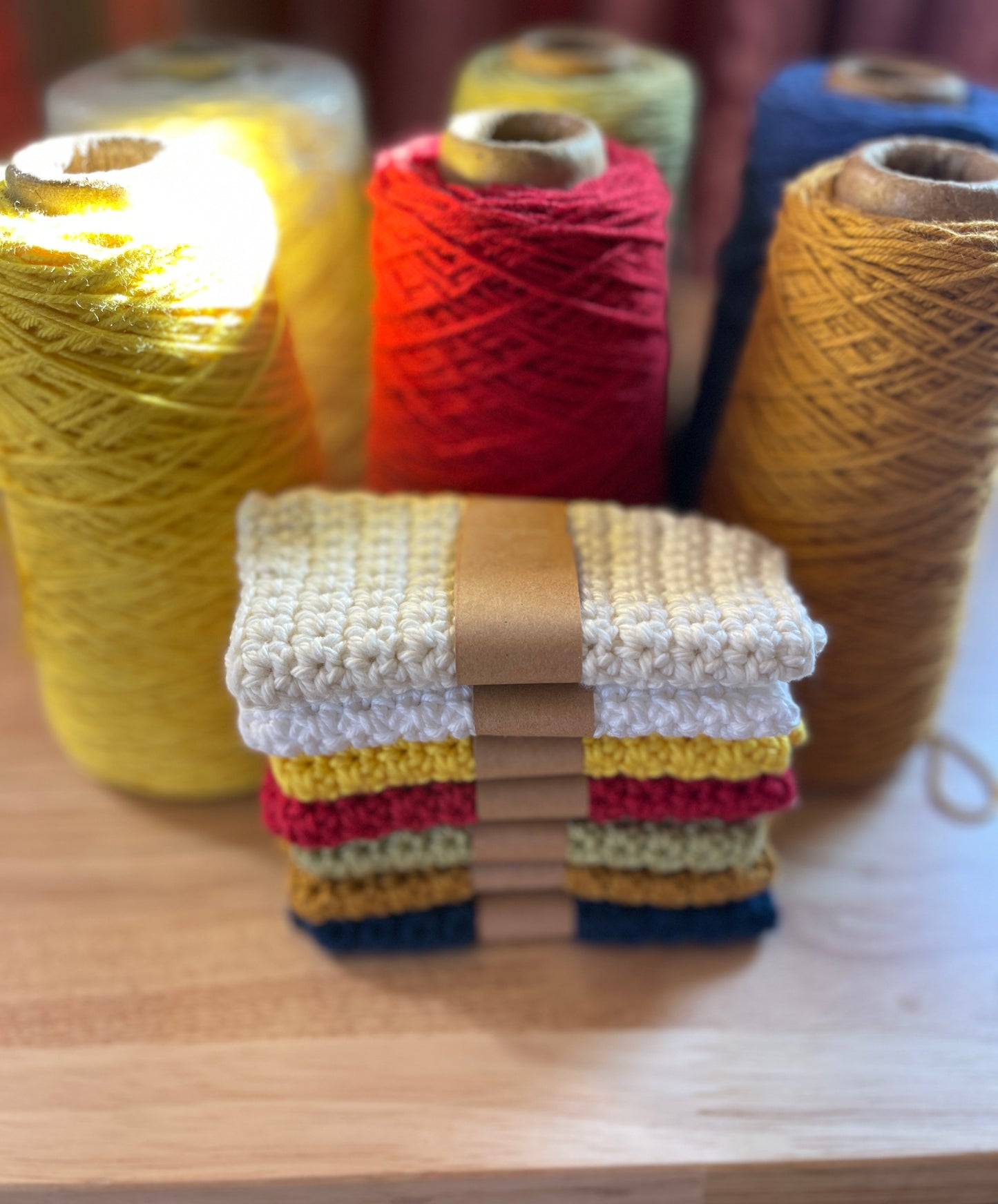 Handmade washcloth on a wood surface  with yarn spools